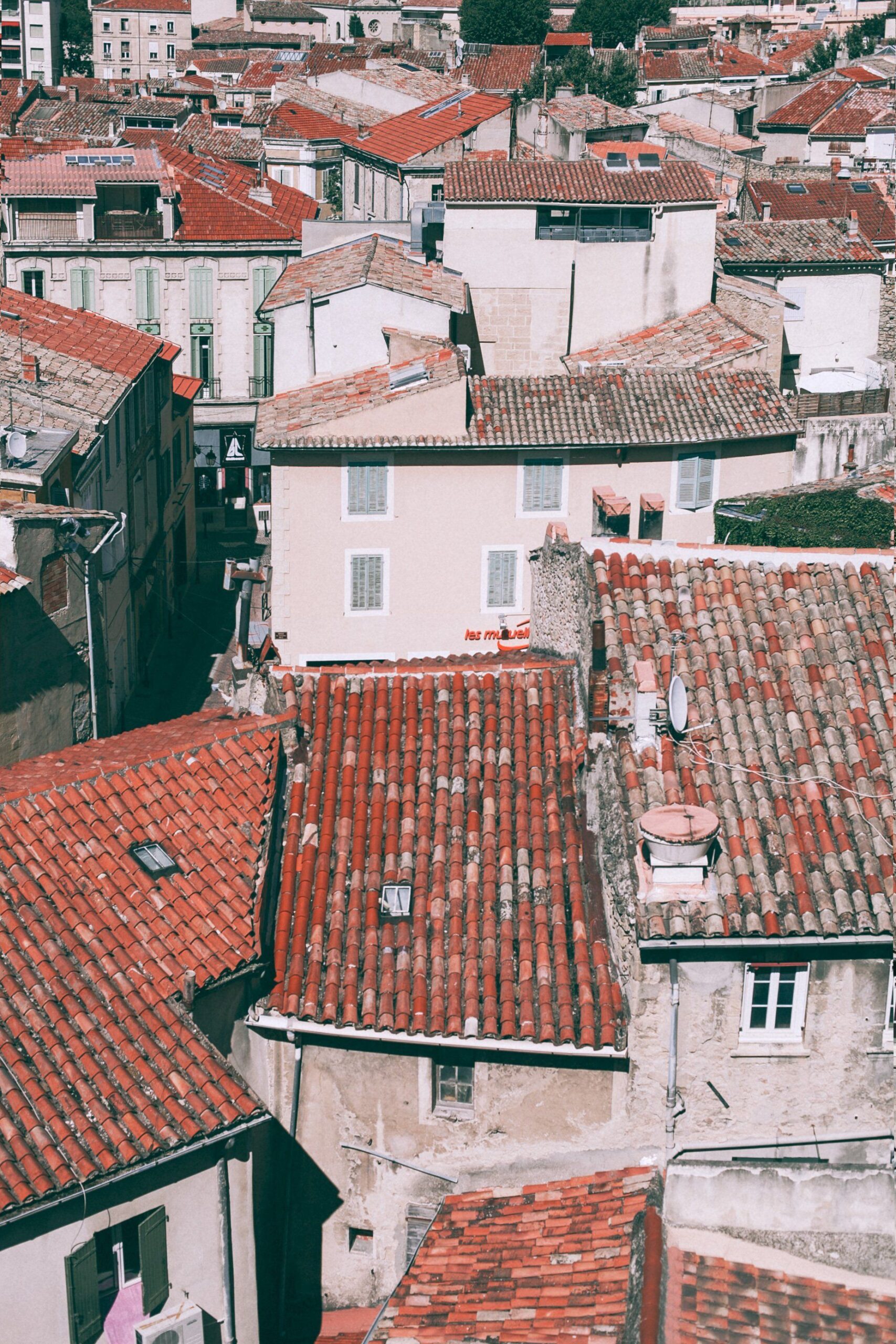 Vista de edificios agrupados con tejados de tejas rojizas, chimeneas, pequeñas ventanas en las cubiertas, antenas y fachadas claras.